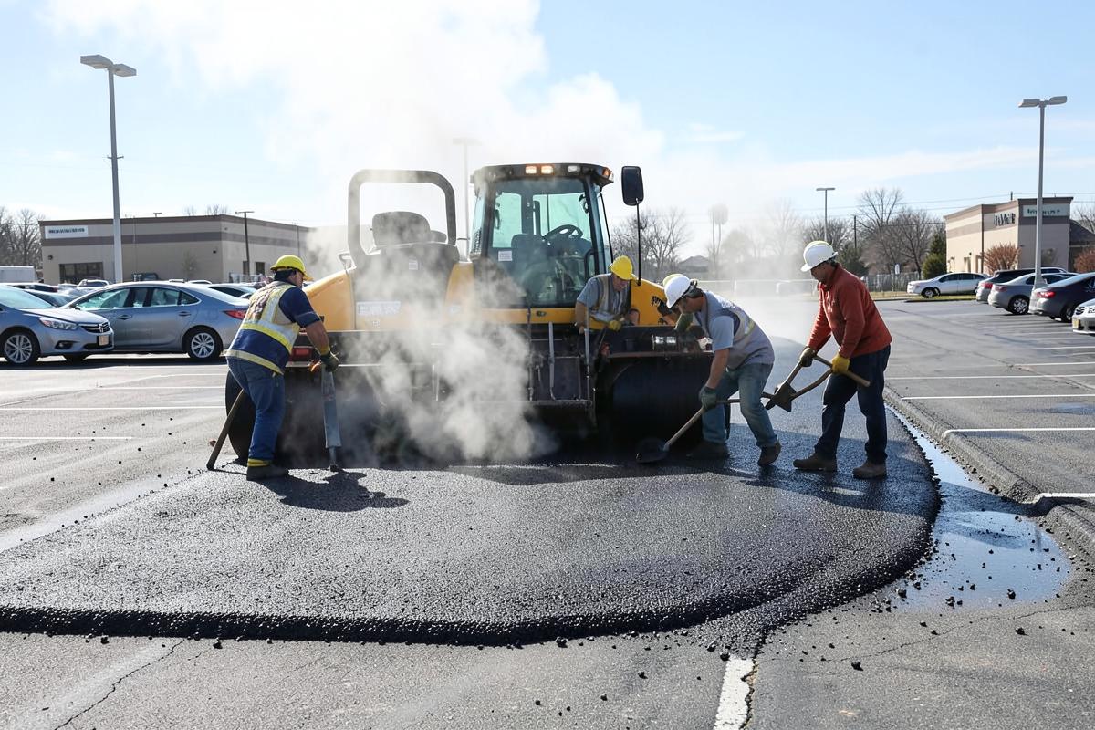 Paving crew placing hot mix asphalt with a paver and roller